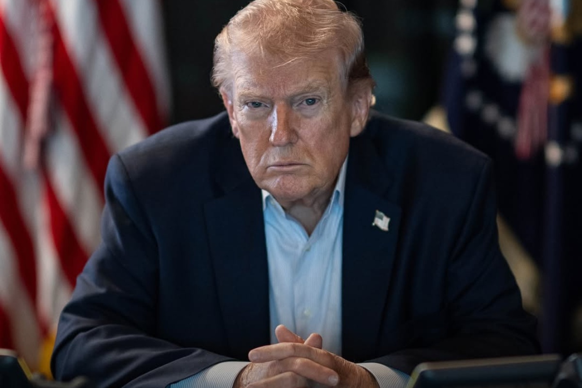 Donald Trump seated in front of American flags