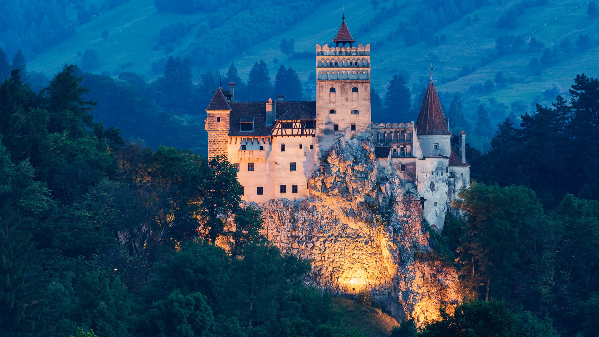 Romanian castle in Transylvania surrounded by forest and blue evening hills